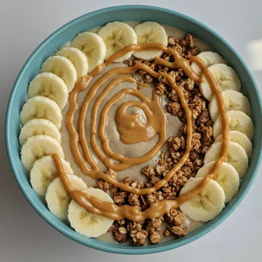 Banana peanut butter smoothie bowl topped with granola and banana