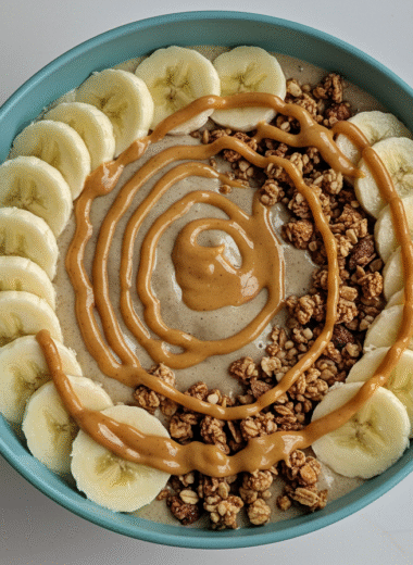 Banana peanut butter smoothie bowl topped with granola and banana